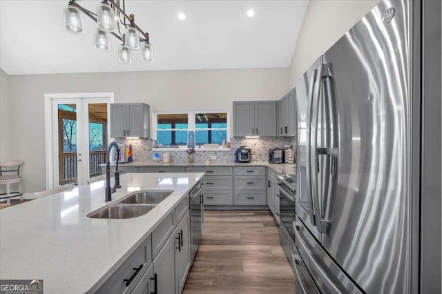 kitchen featuring tasteful backsplash, french doors, appliances with stainless steel finishes, gray cabinetry, and a sink