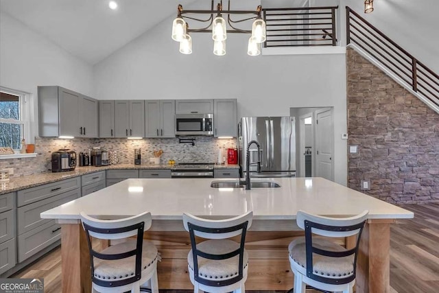 kitchen featuring a sink, high vaulted ceiling, appliances with stainless steel finishes, and gray cabinets