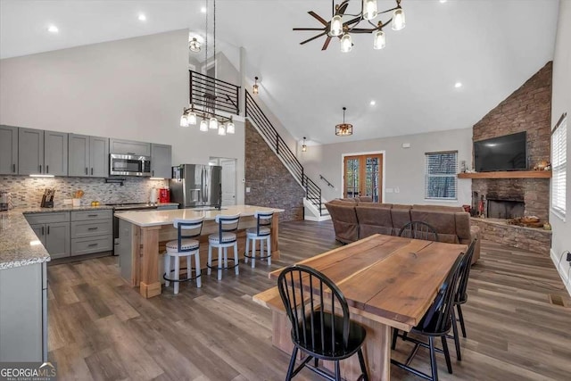 1172 Hunter Dr, Ranger, GA 30734 - dining area featuring high vaulted ceiling, a stone fireplace, dark wood finished floors, a chandelier, and healthy amount of natural light