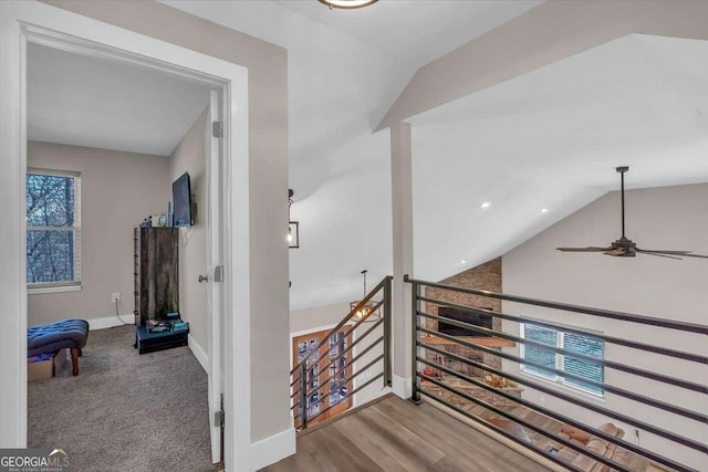 hall with vaulted ceiling, wood finished floors, an upstairs landing, and baseboards