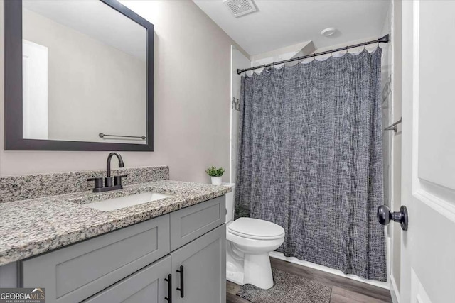 full bathroom featuring toilet, a shower with shower curtain, wood finished floors, vanity, and visible vents