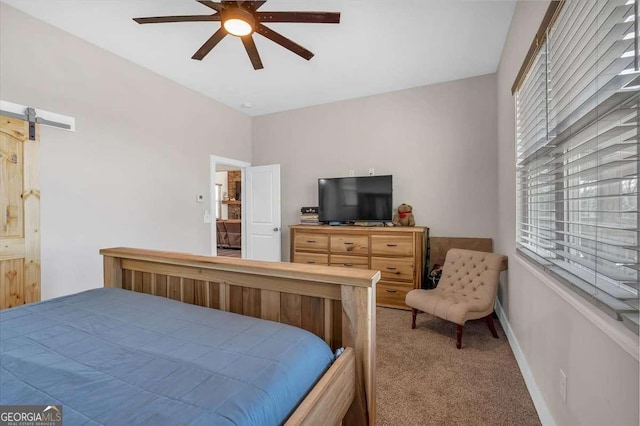 carpeted bedroom with a barn door, baseboards, and ceiling fan