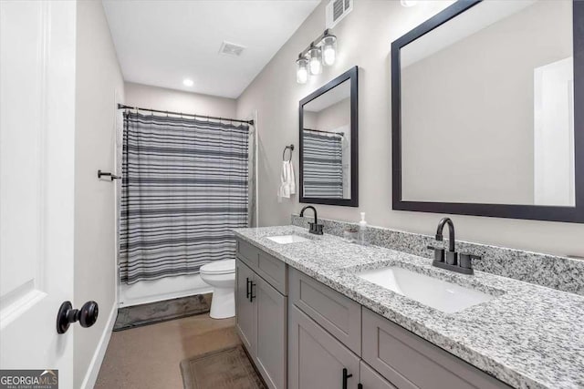 bathroom with visible vents, a sink, toilet, and double vanity