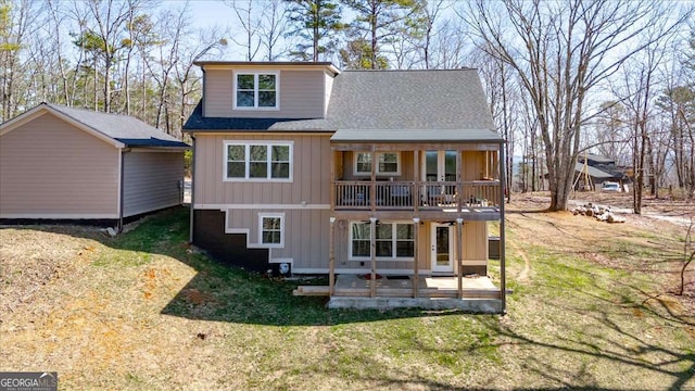 rear view of property with a patio, roof with shingles, and a lawn