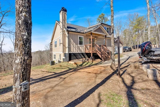 exterior space with central air condition unit, a shingled roof, stairs, and a chimney