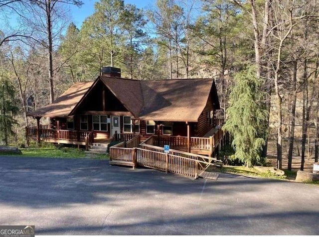 view of front of home with a chimney and a view of trees