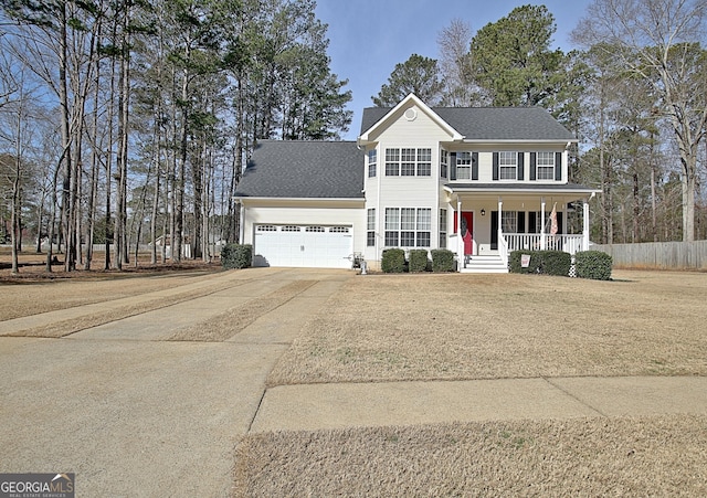 colonial house featuring an attached garage, covered porch, concrete driveway, and roof with shingles