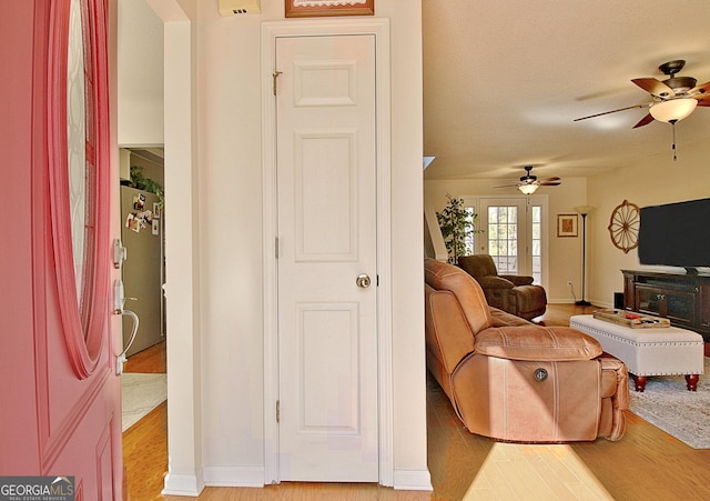 living area featuring a ceiling fan, light wood-type flooring, and baseboards