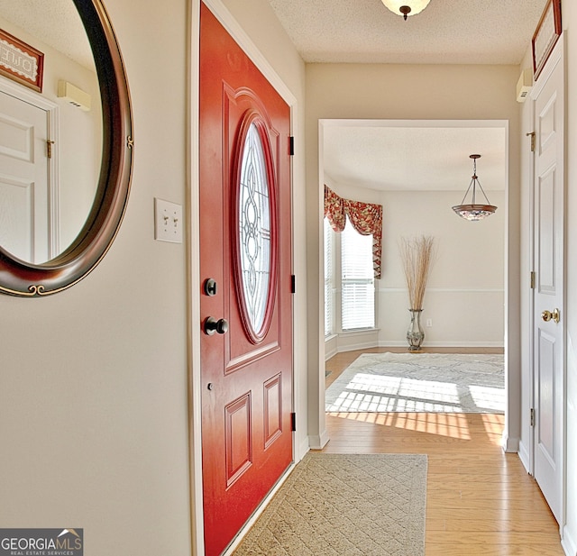 entryway with a textured ceiling, baseboards, and wood finished floors