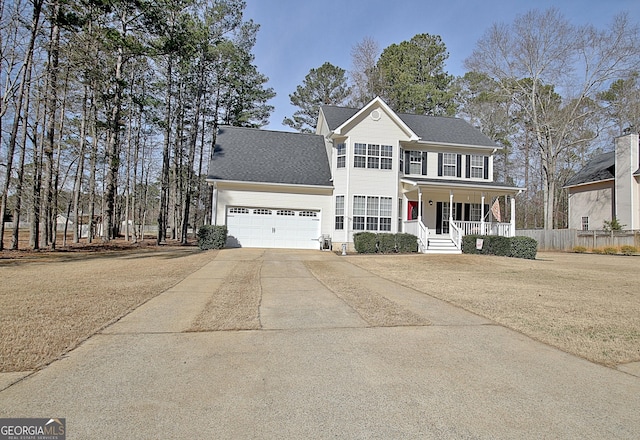 colonial house featuring roof with shingles, concrete driveway, covered porch, a garage, and a front lawn