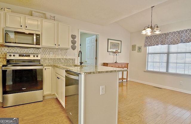 kitchen with visible vents, appliances with stainless steel finishes, a peninsula, light wood-style floors, and a sink