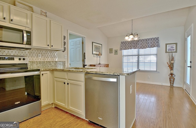 kitchen with light wood-style flooring, light stone counters, a peninsula, stainless steel appliances, and a sink