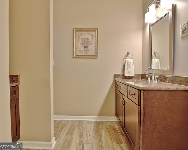 bathroom featuring baseboards, wood finished floors, and vanity