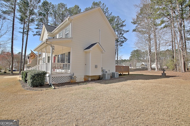 view of side of home featuring a porch, central AC, and a yard