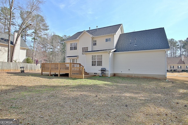 rear view of house featuring a wooden deck, fence, roof with shingles, and a yard