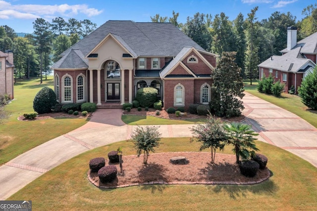 view of front of home with a front yard, brick siding, and driveway