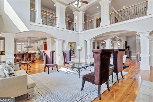 living area featuring arched walkways, decorative columns, and light wood finished floors