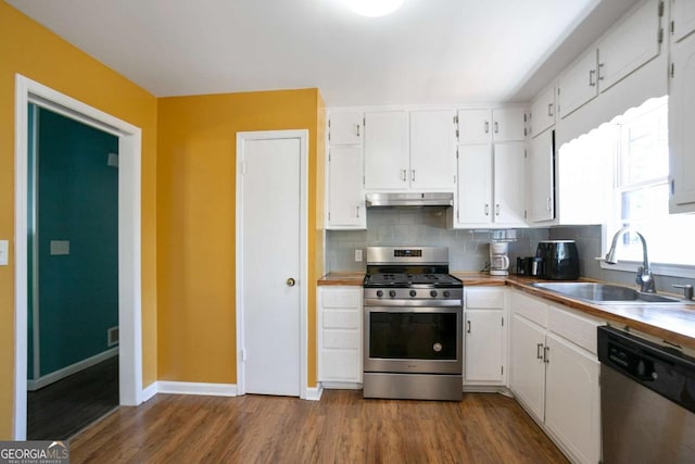 kitchen featuring under cabinet range hood, a sink, white cabinetry, appliances with stainless steel finishes, and decorative backsplash