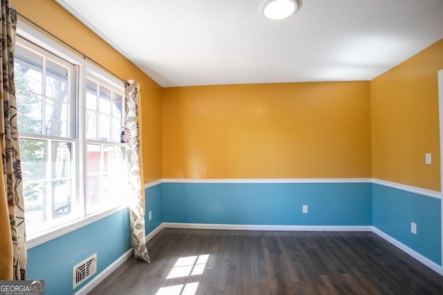 empty room featuring baseboards, plenty of natural light, visible vents, and wood finished floors