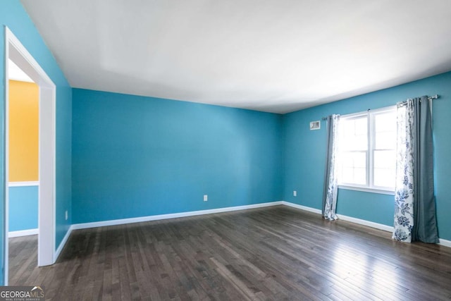 empty room with dark wood-type flooring and baseboards