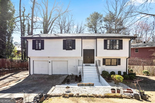 split foyer home featuring brick siding, fence, and an attached garage