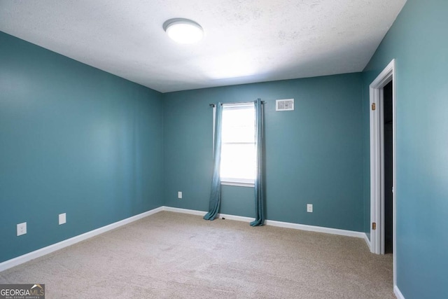 carpeted empty room featuring visible vents, a textured ceiling, and baseboards