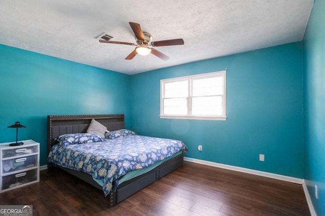 bedroom with a textured ceiling, wood finished floors, visible vents, and baseboards