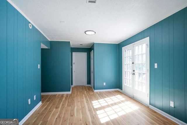 unfurnished room with french doors, ornamental molding, wood finished floors, and baseboards