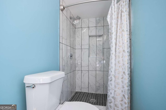 full bathroom with a tile shower and toilet