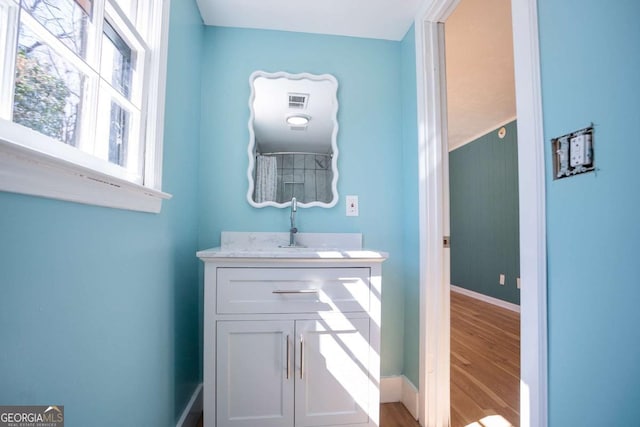 bathroom featuring visible vents, wood finished floors, vanity, and baseboards