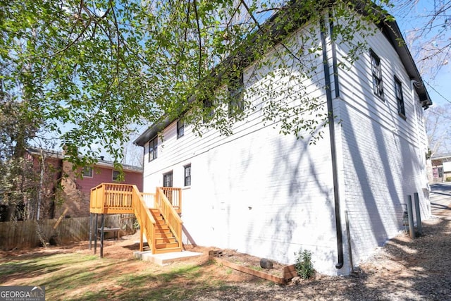 back of house with stairs, a deck, fence, and brick siding