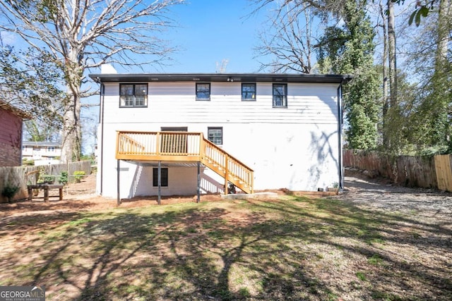 back of property with fence, stairway, a lawn, and a wooden deck