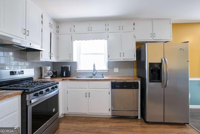 kitchen featuring under cabinet range hood, stainless steel appliances, wood finished floors, a sink, and white cabinets