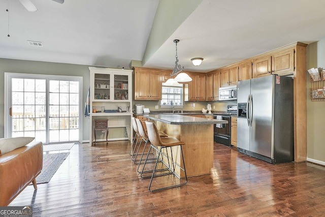 kitchen with visible vents, a kitchen island, appliances with stainless steel finishes, and dark wood-style floors