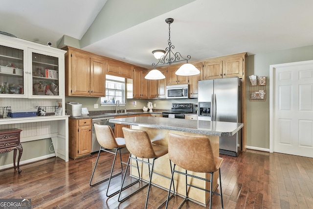 kitchen featuring a center island, dark wood finished floors, a breakfast bar area, stainless steel appliances, and a sink