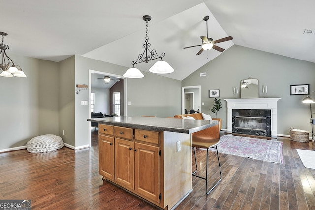 kitchen featuring dark countertops, a center island, dark wood-style flooring, and ceiling fan