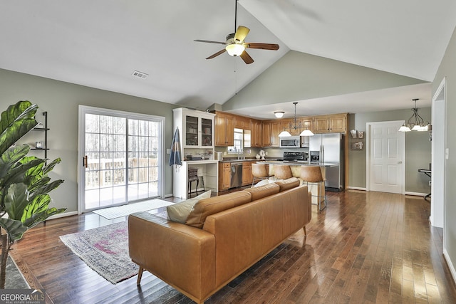 living room featuring visible vents, high vaulted ceiling, dark wood finished floors, and ceiling fan with notable chandelier