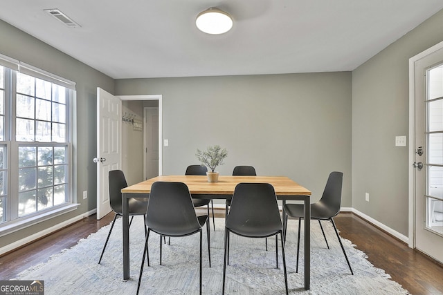 dining area with dark wood-style floors, visible vents, and baseboards