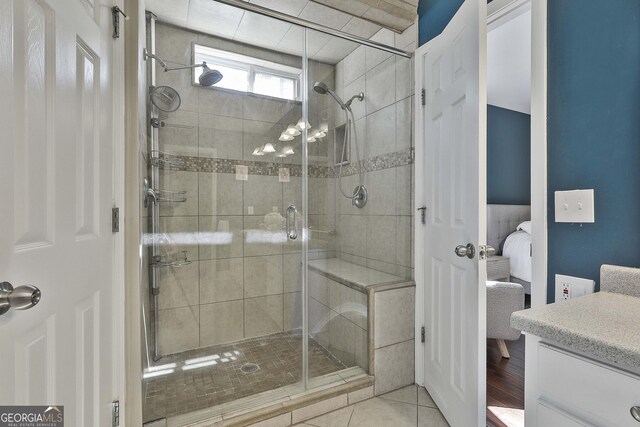 bathroom with tile patterned floors, connected bathroom, a stall shower, and vanity