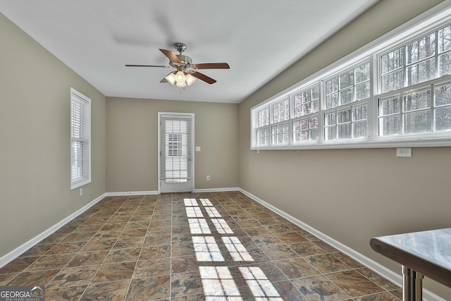 interior space featuring stone finish flooring, baseboards, and ceiling fan