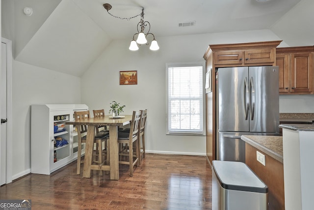 kitchen with visible vents, lofted ceiling, freestanding refrigerator, dark wood-type flooring, and brown cabinets