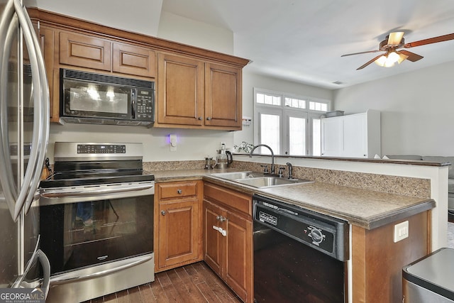 kitchen with black appliances, brown cabinetry, a peninsula, and a sink