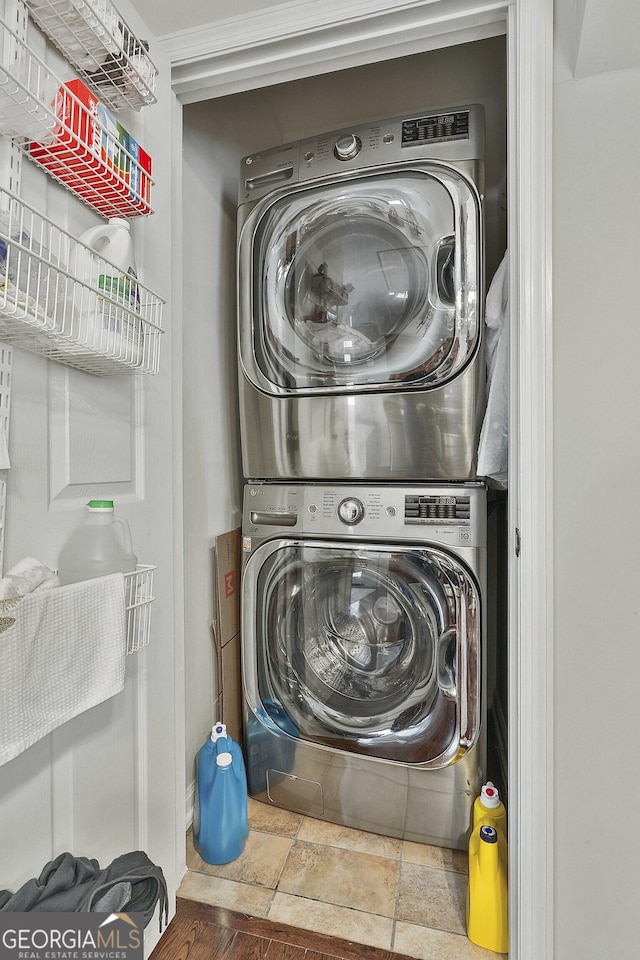 clothes washing area with stone tile flooring and stacked washer / drying machine