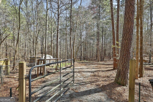 view of yard featuring a gate, a view of trees, and fence