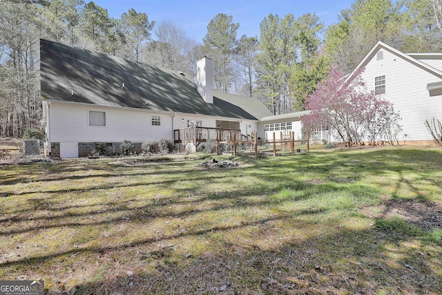 rear view of house with a lawn, a chimney, and a deck