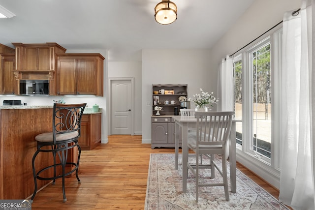 kitchen with black microwave, light countertops, brown cabinetry, and light wood-type flooring