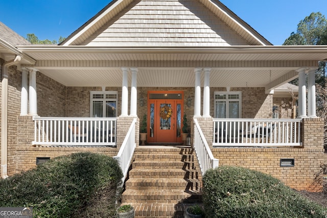 view of exterior entry with covered porch and brick siding