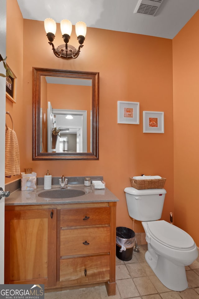 half bathroom with visible vents, toilet, tile patterned floors, vanity, and a notable chandelier