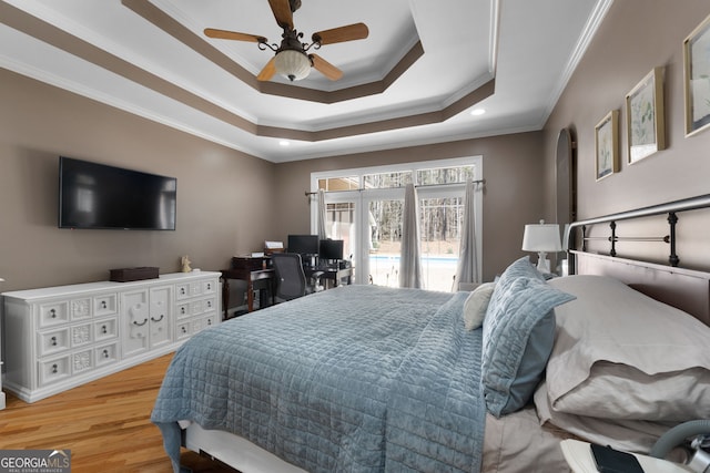 bedroom featuring arched walkways, light wood-style flooring, access to outside, ornamental molding, and a raised ceiling