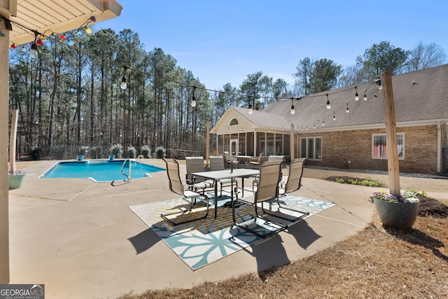 pool with a patio, outdoor dining area, and a sunroom